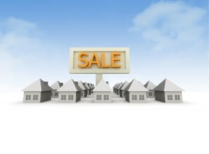 Small white houses with big sale sign behind