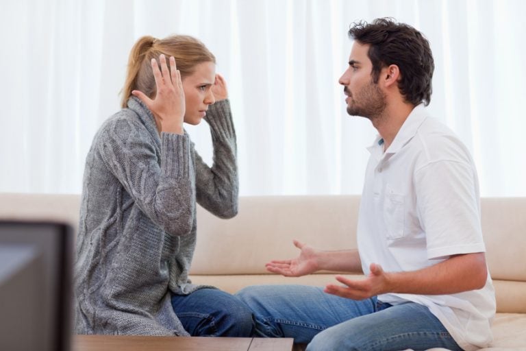 Couple arguing on a sofa during a tense relationship breakdown relevant to tenancy issues