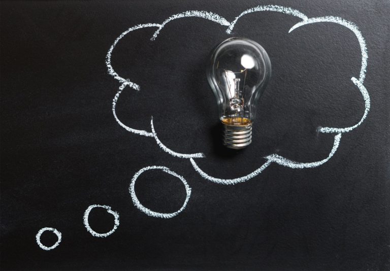 Lightbulb on chalkboard inside a thought bubble representing new ideas and innovation.
