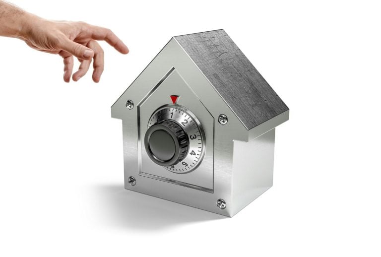 Hand reaching toward a house-shaped safe representing secure rental deposits