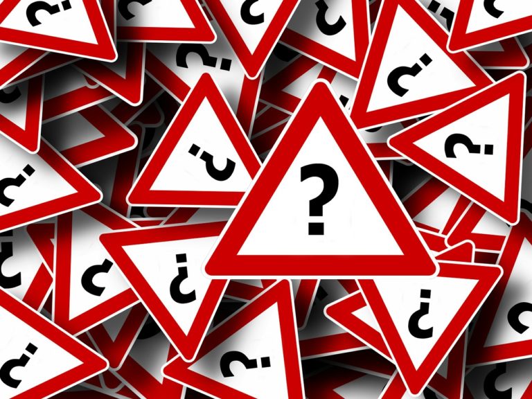 Pile of red warning signs with question marks symbolizing confusion or legal uncertainty.