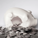 White piggy bank tipped over with coins spilling out, symbolising rent arrears and financial loss