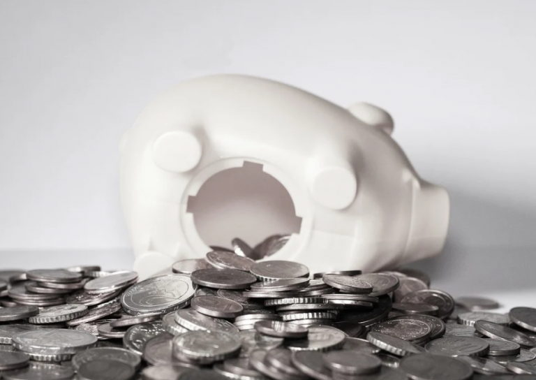 White piggy bank tipped over with coins spilling out, symbolising rent arrears and financial loss