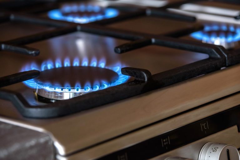 Gas hob burner with blue flame during operation, relating to gas safety checks after appliance repairs
