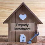 A wooden house with a key against a wooden backdrop for landlord investors