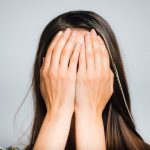 Person covering face with hands, representing stress or regret over legal or financial issues