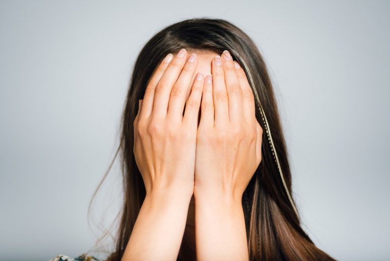 Person covering face with hands, representing stress or regret over legal or financial issues