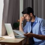 Man reviewing tenant issue at desk with documents and laptop