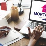 Person researching mortgage options on a laptop while taking notes