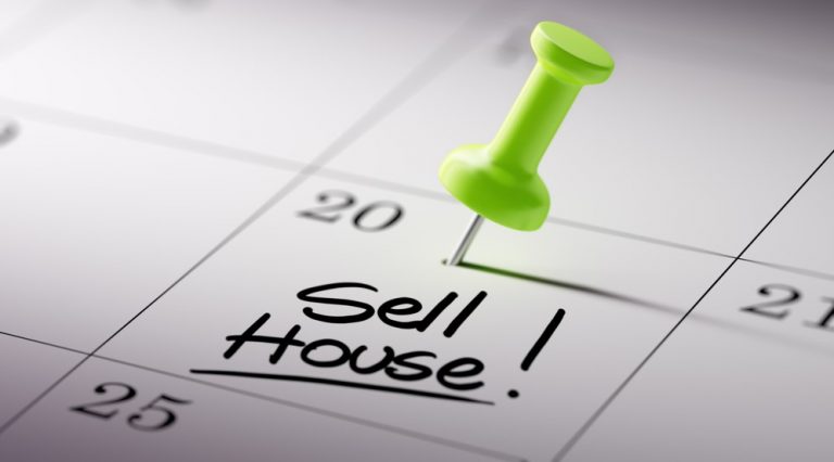Calendar with green pin marking date and note to sell house.