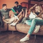 Students discussing housing plans in a shared living room.