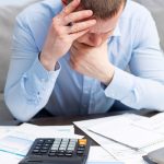 Stressed landlord reviewing bills and finances with calculator on desk