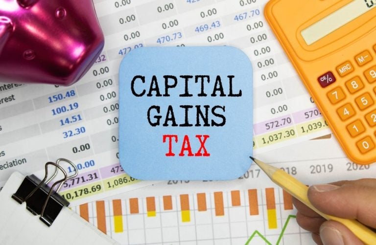 Capital Gains Tax, a yellow calculator on a desk with papers, a pen and a paper clip.