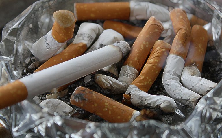 Cigarette butts filling an ashtray, symbolizing smoking hazards and fire risk.