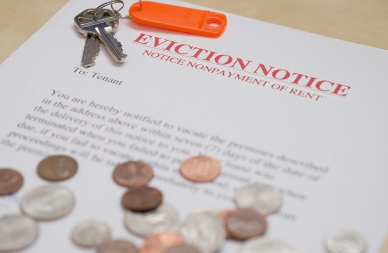 Eviction notice with keys and scattered coins highlighting rent arrears