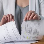 Person tearing a rental contract in half, symbolizing landlord licence or tenancy breach.