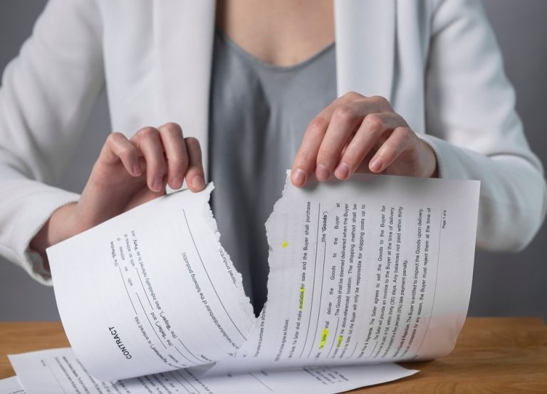 Person tearing a rental contract in half, symbolizing landlord licence or tenancy breach.