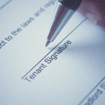 Close-up of a tenancy agreement being signed by a tenant