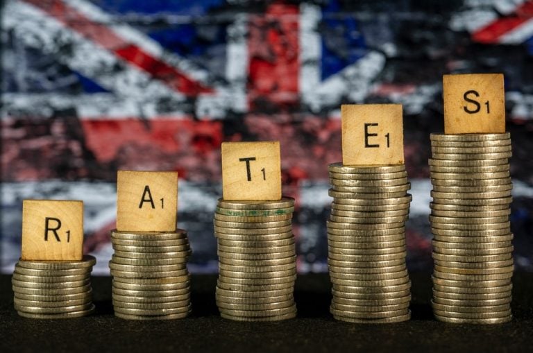 Rates spelled out on stacked coins with UK flag in the background