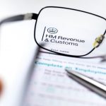 HMRC documents viewed through glasses with a pen nearby, illustrating property tax implications