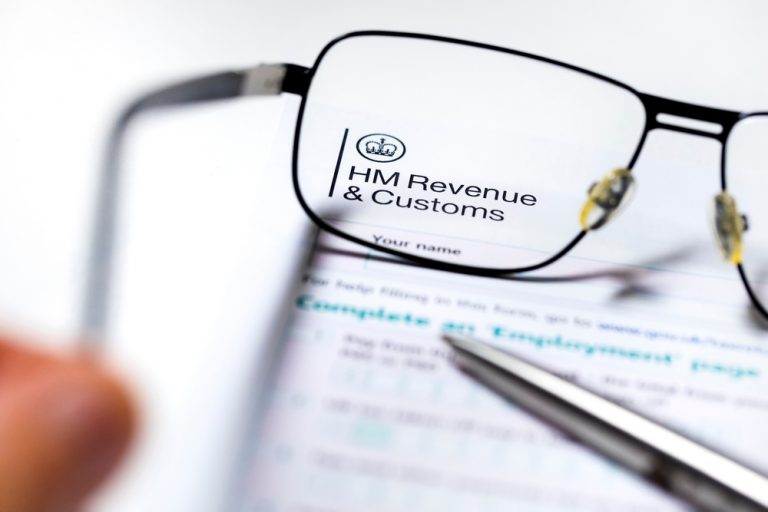 HMRC documents viewed through glasses with a pen nearby, illustrating property tax implications