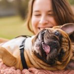 Happy tenant holding a playful French Bulldog outdoors, highlighting pet-friendly rental rights.