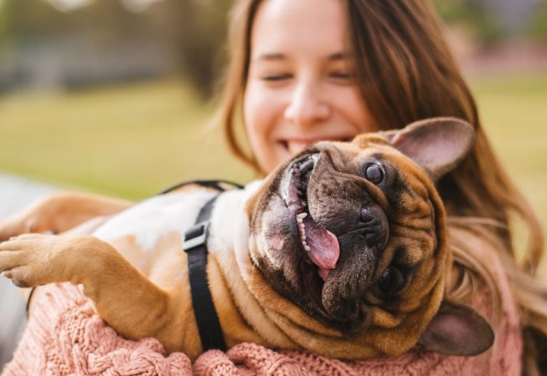Happy tenant holding a playful French Bulldog outdoors, highlighting pet-friendly rental rights.