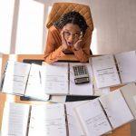 Landlord overwhelmed by paperwork and financial documents while managing rental property changes.