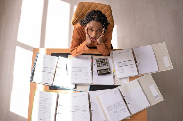 Landlord overwhelmed by paperwork and financial documents while managing rental property changes.