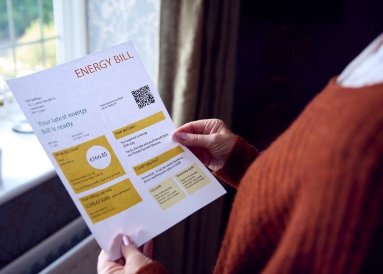 Person holding an energy bill while reviewing household energy costs.