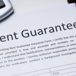 Close-up of a Rent Guarantee contract with pen and calculator.