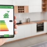 Smartphone showing smart home energy efficiency rating in a modern kitchen