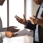Two professionals discussing withheld landlord documents during a property handover.