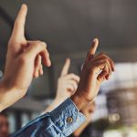 Raised hands in a discussion symbolizing participation and questioning leadership purpose.