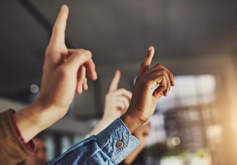 Raised hands in a discussion symbolizing participation and questioning leadership purpose.