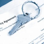 Key resting on tenancy agreement paperwork relating to a rental arrangement for multiple occupants
