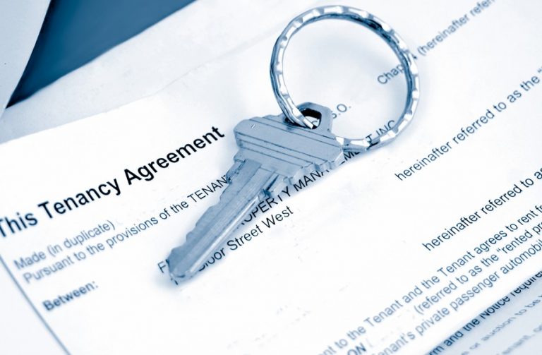 Key resting on tenancy agreement paperwork relating to a rental arrangement for multiple occupants