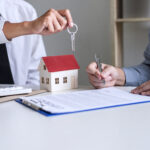 Real estate Sales manager giving keys to customer after signing rental lease contract of sale purchase agreement, concerning mortgage loan offer for and house insurance.