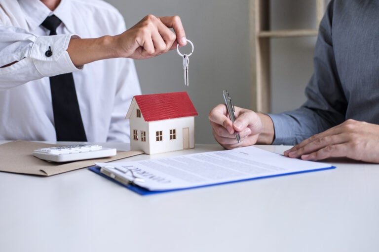 Real estate Sales manager giving keys to customer after signing rental lease contract of sale purchase agreement, concerning mortgage loan offer for and house insurance.