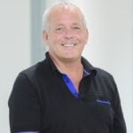 Smiling man standing in a bright hallway related to rising rental market demand