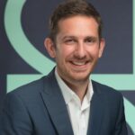 Business professional smiling in formal attire during interview about landlord portfolio diversification