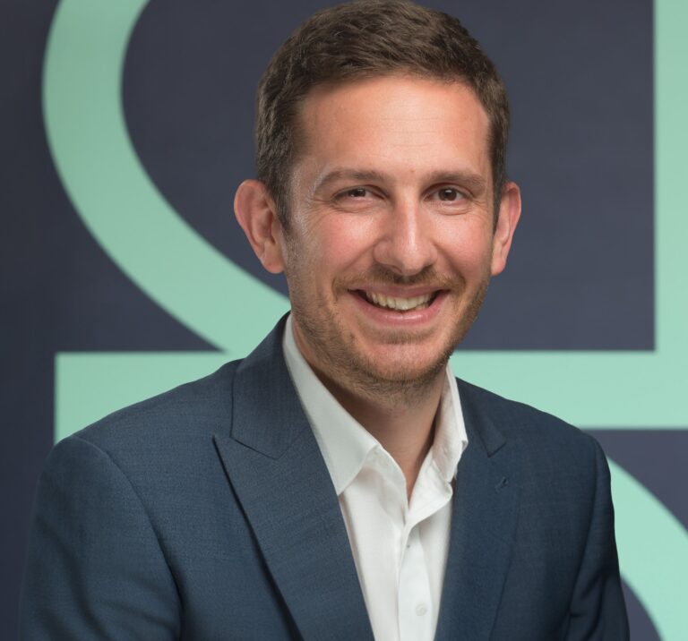 Business professional smiling in formal attire during interview about landlord portfolio diversification