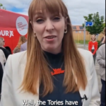 Angela Rayner wearing a "Vote Labour" necklace standing in front of a campaign bus.