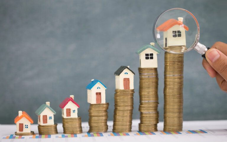 Rising house prices compared to income growth shown with houses on stacked coins