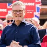 Keir Starmer at a Labour campaign event with supporters holding red signs and Union Jack flags