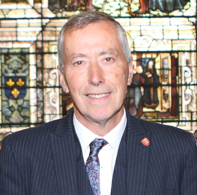 Council leader speaking on housing reform in front of stained-glass backdrop