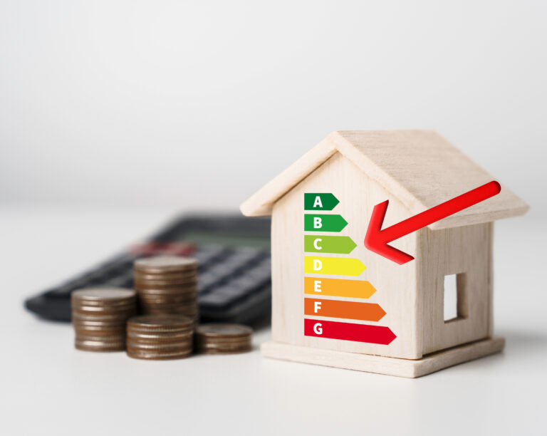 Wooden house model with EPC rating chart and red arrow beside stacked coins and calculator