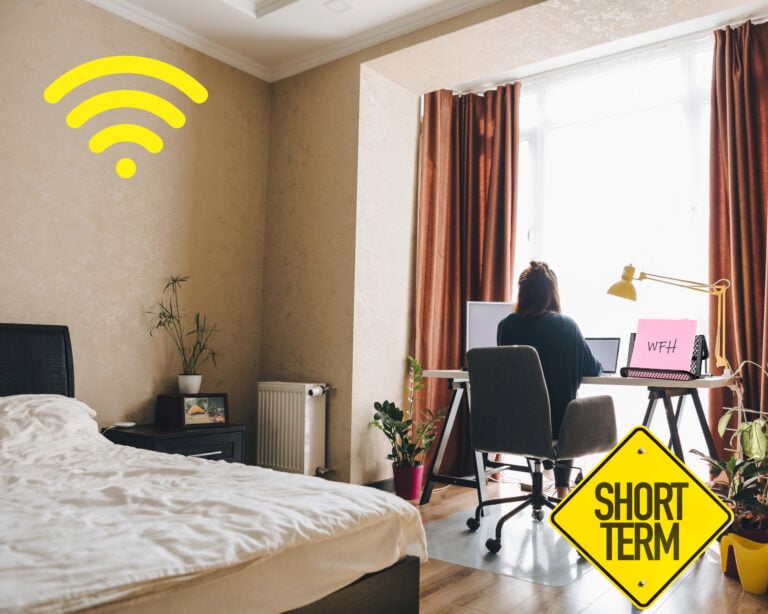 Remote worker using a laptop in a bright live-work rental space designed for short-term flexibility