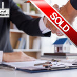 Handshake over property sale documents with keys as a local authority finalises the purchase of a tenanted home