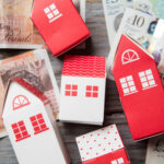 Paper houses displayed on top of UK banknotes to illustrate funding pressures on social housing